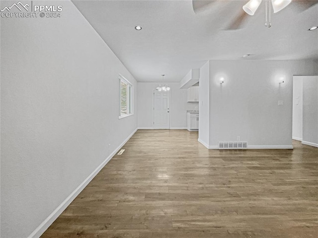 unfurnished living room with hardwood / wood-style floors and ceiling fan with notable chandelier