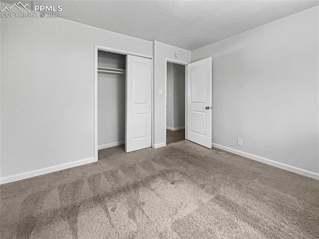 unfurnished bedroom with a closet and dark colored carpet