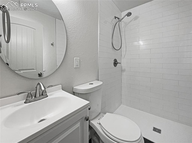 bathroom with vanity, toilet, and a tile shower