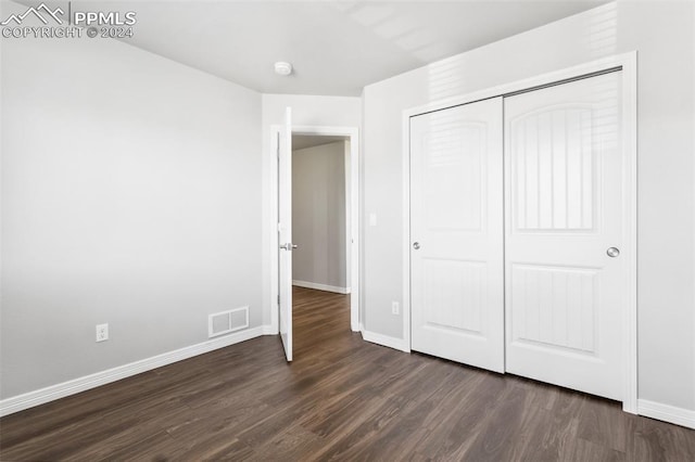 unfurnished bedroom with a closet and dark wood-type flooring