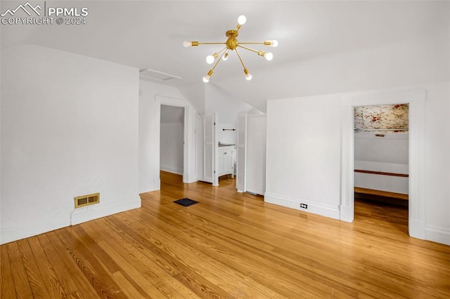 unfurnished room featuring light wood-type flooring and an inviting chandelier