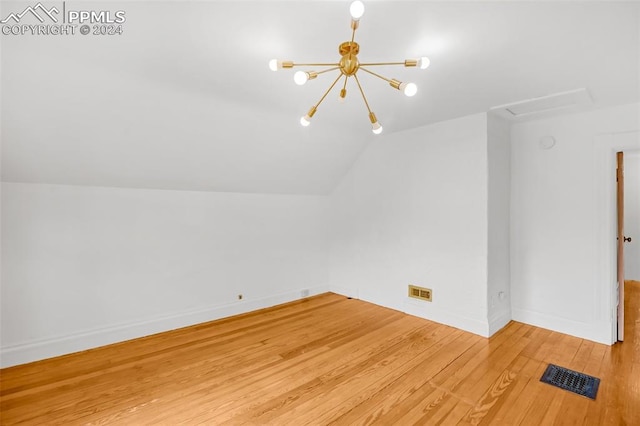 additional living space featuring hardwood / wood-style floors, a chandelier, and lofted ceiling