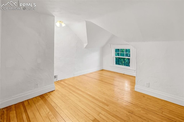 additional living space with hardwood / wood-style flooring and lofted ceiling