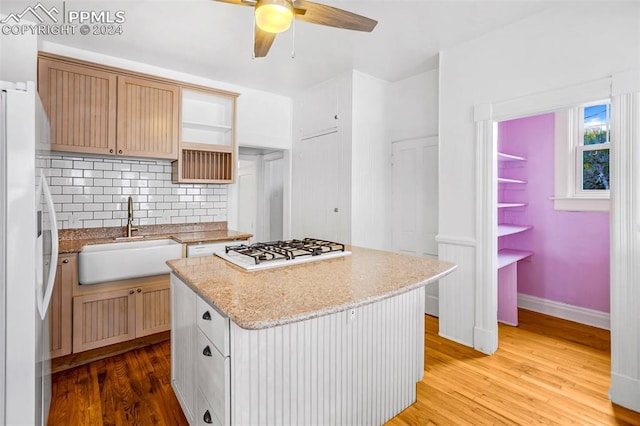 kitchen with a center island, sink, tasteful backsplash, light hardwood / wood-style flooring, and white appliances