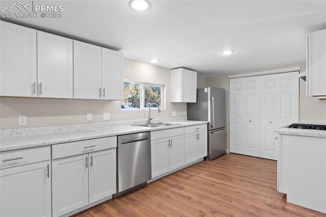 kitchen featuring sink, white cabinets, stainless steel appliances, and light hardwood / wood-style floors