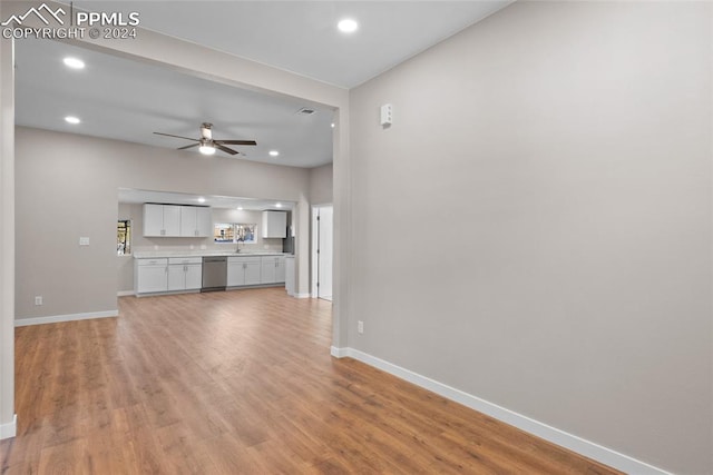 unfurnished living room with ceiling fan, wood-type flooring, and sink