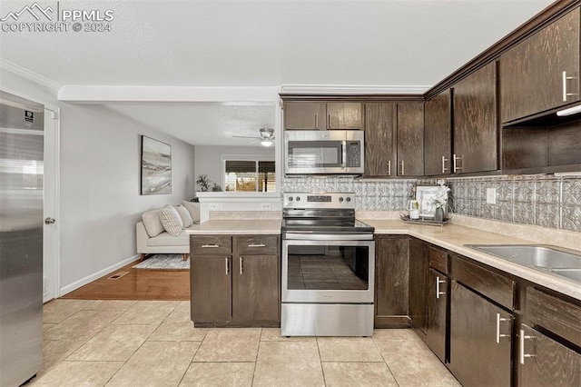 kitchen featuring tasteful backsplash, ornamental molding, dark brown cabinets, stainless steel appliances, and light tile patterned floors