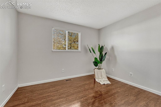 empty room with dark hardwood / wood-style floors and a textured ceiling