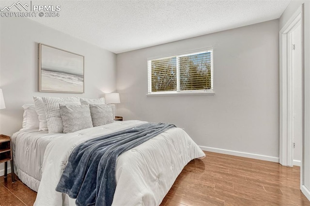 bedroom with wood-type flooring and a textured ceiling