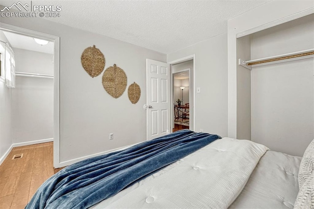 bedroom with a closet, wood-type flooring, and a textured ceiling