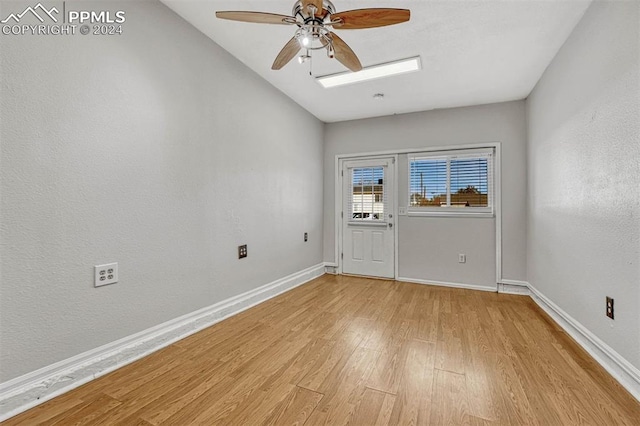 unfurnished room with light wood-type flooring, a skylight, and ceiling fan