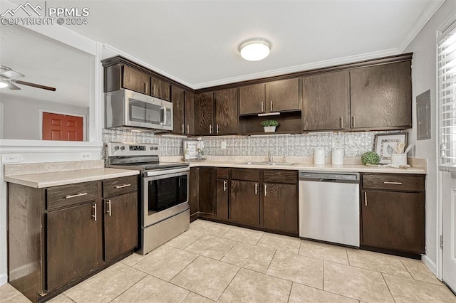 kitchen with appliances with stainless steel finishes, tasteful backsplash, ornamental molding, dark brown cabinets, and sink