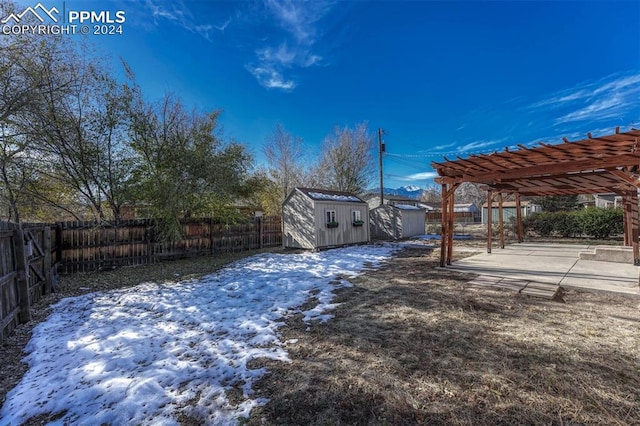 yard layered in snow with a pergola, a patio, and a shed