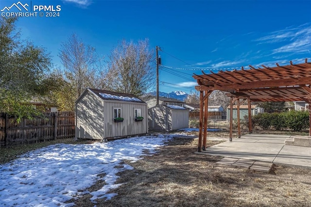 yard covered in snow with a patio area, a pergola, and a storage shed