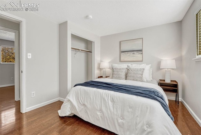 bedroom featuring a textured ceiling, a closet, and dark wood-type flooring