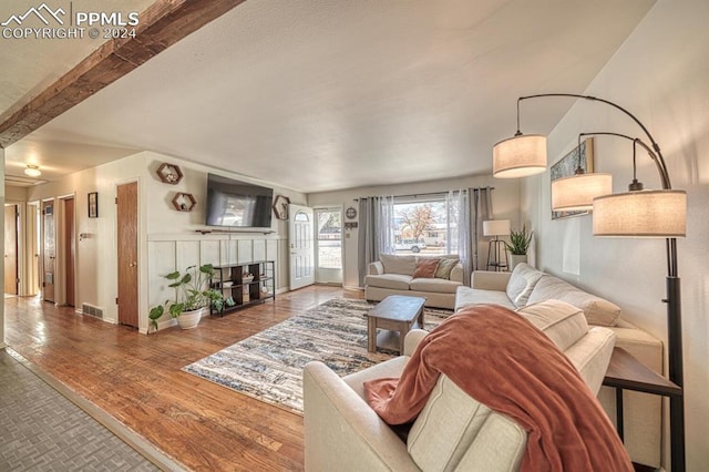 1511 N Chelton Rd, Colorado Springs, CO 80909 - living area featuring a tiled fireplace, wood finished floors, and beamed ceiling