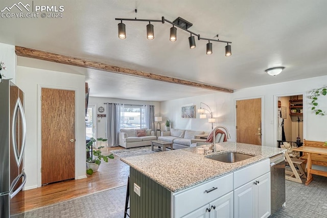 1511 N Chelton Rd, Colorado Springs, CO 80909 - kitchen featuring a sink, stainless steel appliances, a center island with sink, light stone countertops, and beamed ceiling