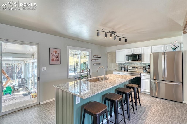 1511 N Chelton Rd, Colorado Springs, CO 80909 - kitchen with stainless steel appliances, a sink, white cabinets, a kitchen breakfast bar, and light colored carpet