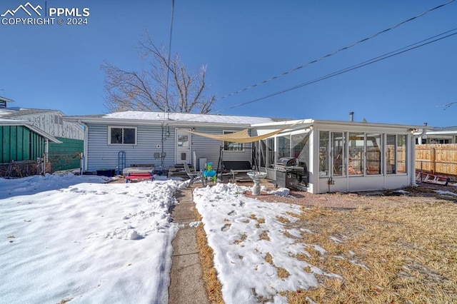 snow covered house featuring a sunroom