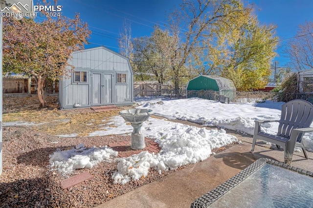 yard layered in snow with a storage unit