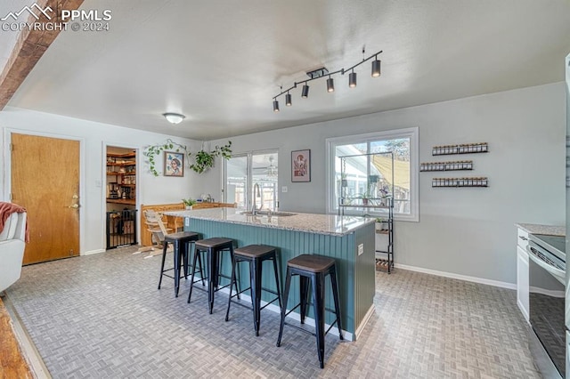 kitchen featuring sink, a kitchen island with sink, stainless steel range, a breakfast bar, and light wood-type flooring