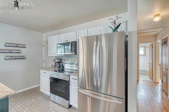 kitchen with white cabinets, light wood-type flooring, appliances with stainless steel finishes, and light stone counters