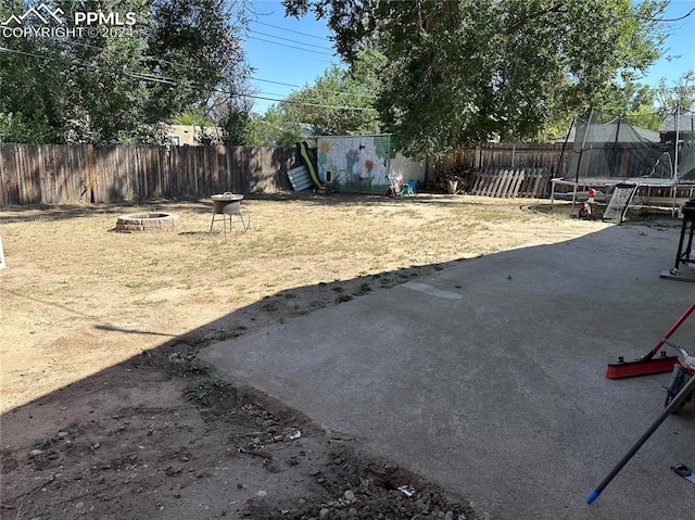 view of yard with a patio area, a trampoline, and an outdoor fire pit