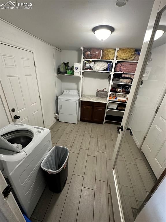 clothes washing area featuring washing machine and dryer and light hardwood / wood-style flooring