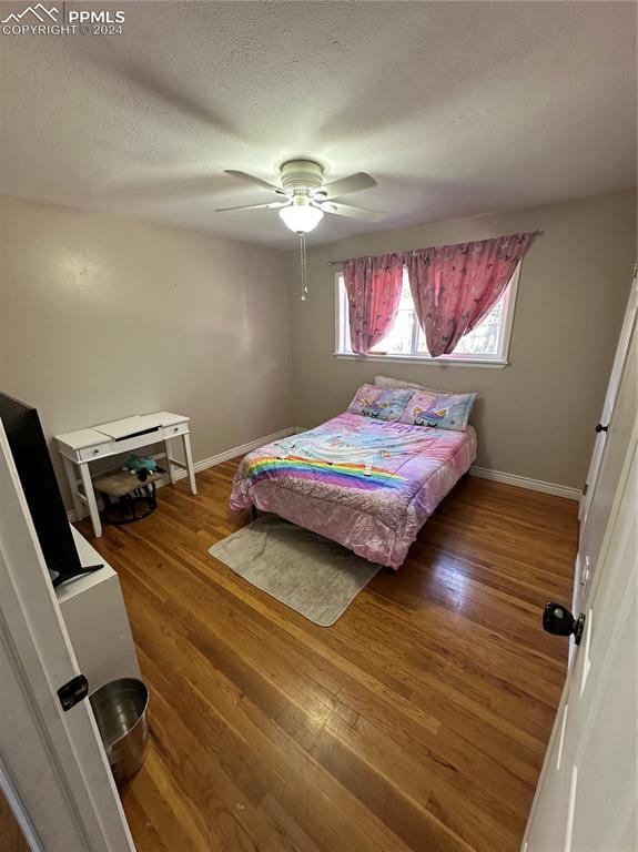 bedroom featuring ceiling fan, wood-type flooring, and a textured ceiling