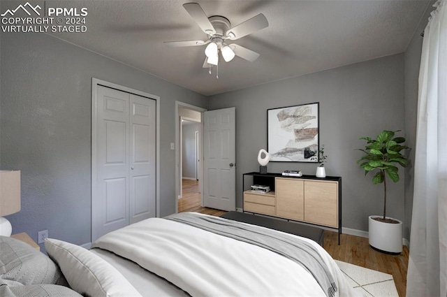 bedroom featuring a textured ceiling, light hardwood / wood-style floors, ceiling fan, and a closet