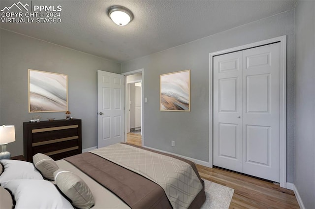 bedroom with light hardwood / wood-style floors, a textured ceiling, and a closet