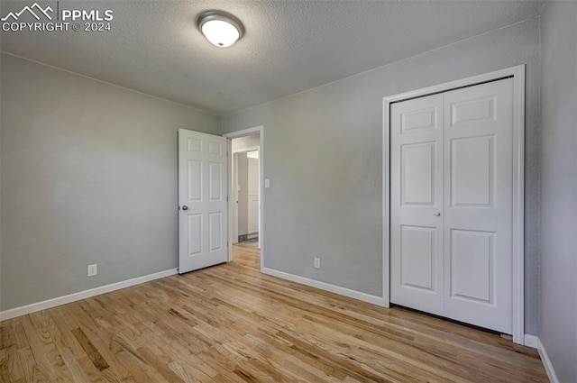 unfurnished bedroom with a closet, a textured ceiling, and light hardwood / wood-style flooring