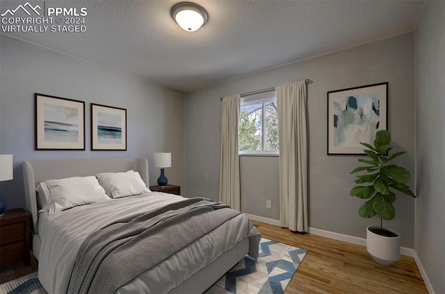 bedroom with light wood-type flooring and a textured ceiling