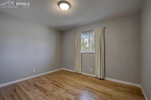 empty room with light hardwood / wood-style flooring and a textured ceiling