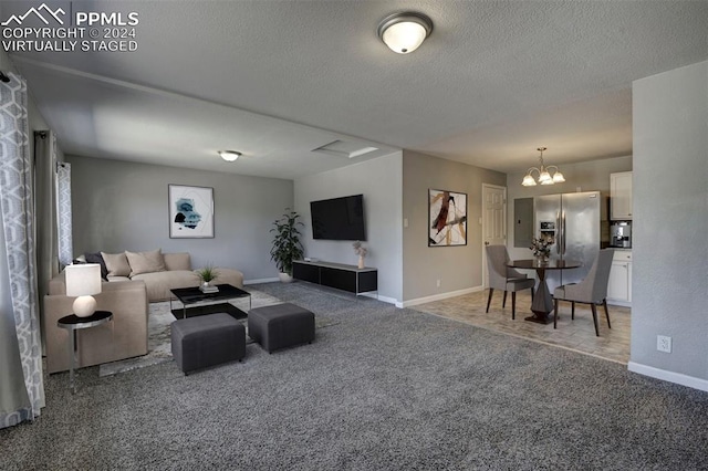 living room featuring carpet, a textured ceiling, and an inviting chandelier