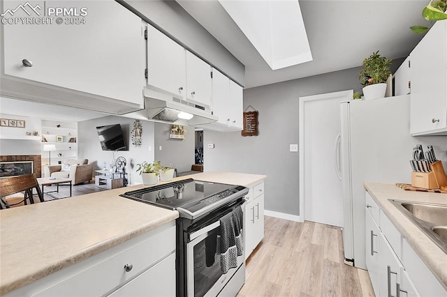 kitchen featuring a skylight, stainless steel electric range oven, light hardwood / wood-style flooring, and white cabinets