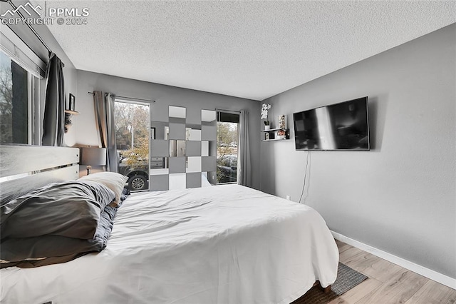 bedroom with a textured ceiling and light hardwood / wood-style flooring