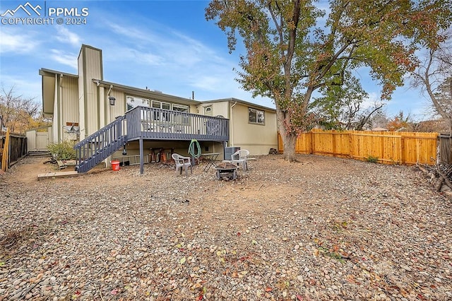 rear view of property with a fire pit, cooling unit, and a wooden deck