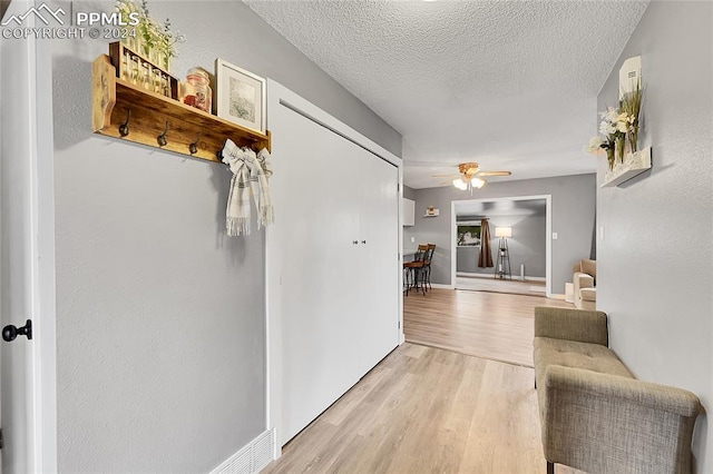 corridor featuring light hardwood / wood-style floors and a textured ceiling