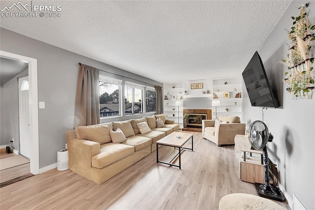 living room with a fireplace, light hardwood / wood-style flooring, and a textured ceiling