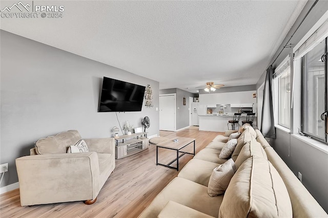 living room with ceiling fan, light hardwood / wood-style floors, and a textured ceiling