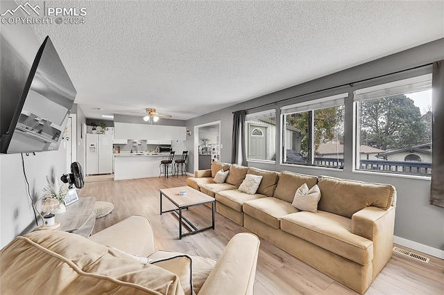 living room featuring a textured ceiling, light hardwood / wood-style flooring, and ceiling fan