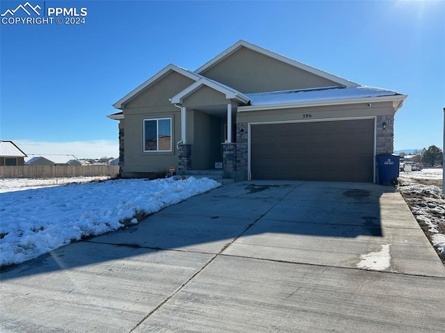 view of front facade with concrete driveway, an attached garage, fence, and stucco siding