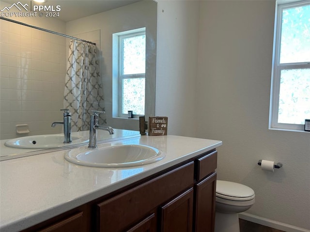 bathroom with walk in shower, vanity, and toilet