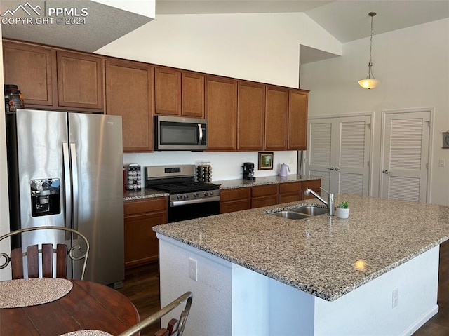 kitchen featuring sink, a center island with sink, hanging light fixtures, appliances with stainless steel finishes, and light stone counters