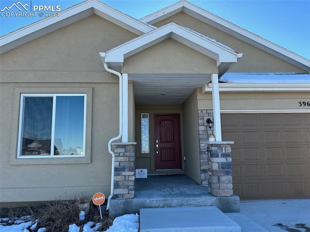 property entrance with a garage, stone siding, and stucco siding