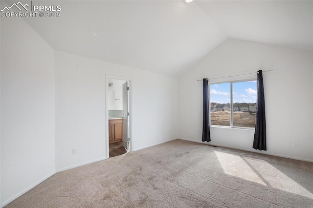 interior space with connected bathroom, baseboards, vaulted ceiling, and carpet flooring