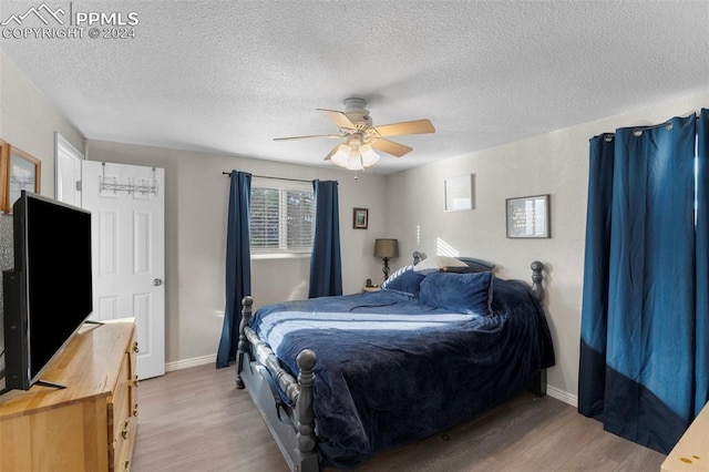 bedroom with ceiling fan, light hardwood / wood-style floors, and a textured ceiling