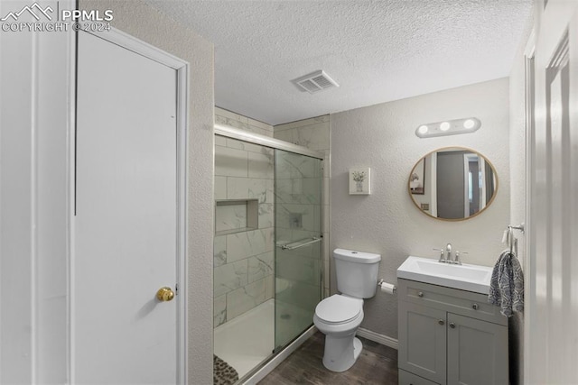 bathroom with hardwood / wood-style floors, a textured ceiling, toilet, and walk in shower