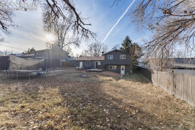 back of property with a yard and a trampoline